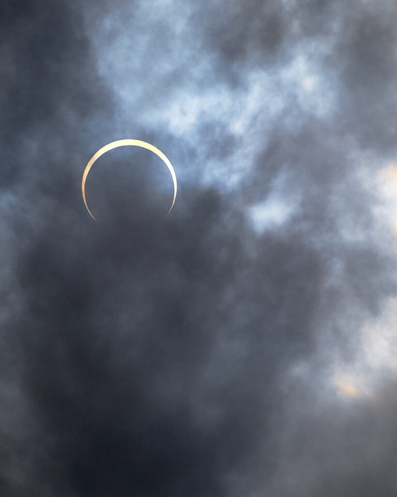 Desde mi balcón, presencio un eclipse anular de sol. La luna, en su órbita, se alinea perfectamente con el sol, creando un halo de luz dorada alrededor de la sombra oscura del astro rey. Es un momento fugaz de belleza cósmica que cautiva mis sentidos.