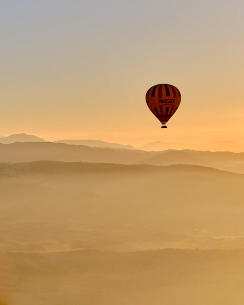 Un globo aerostático solitario se eleva en el horizonte bajo el amanecer.